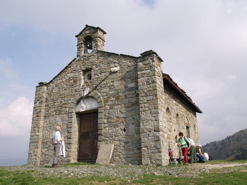 La Cappella nei pressi del Passo del Cirone, restaurata e già rovinata. Mino osserva la sculture, Franca tra poco suonerà la campana.