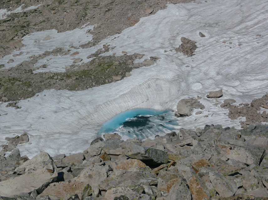 Laggiù in basso la sterminata pietraia viene ingentilita da questo minuscolo laghetto ghiacciato color verde smeraldo