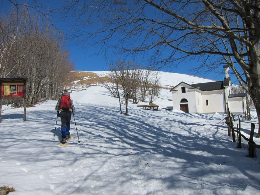 La casa del Musante e la chiesetta, poi la cupola arrotondata della vetta. La neve lascia spazio anche all'erba. Alcune figurine si muovono intorno alla croce