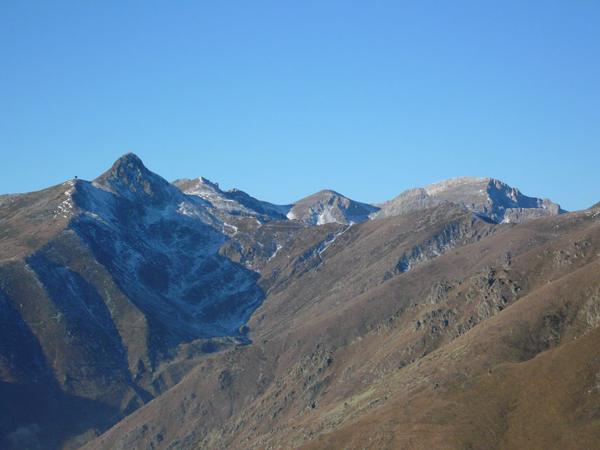 A est il panorama si allarga sulla testata della Val d’Armella, con la conca del Lago del Pizzo parzialmente in ombra e ancora desolatamente spoglia di neve. Al di là della Colla del Pizzo e dello spartiacque Tanaro-Corsaglia, si scorgono (da sinistra a destra) la Cima delle Roccate, il Monte Rotondo, la Cima Revelli e il Mongioie